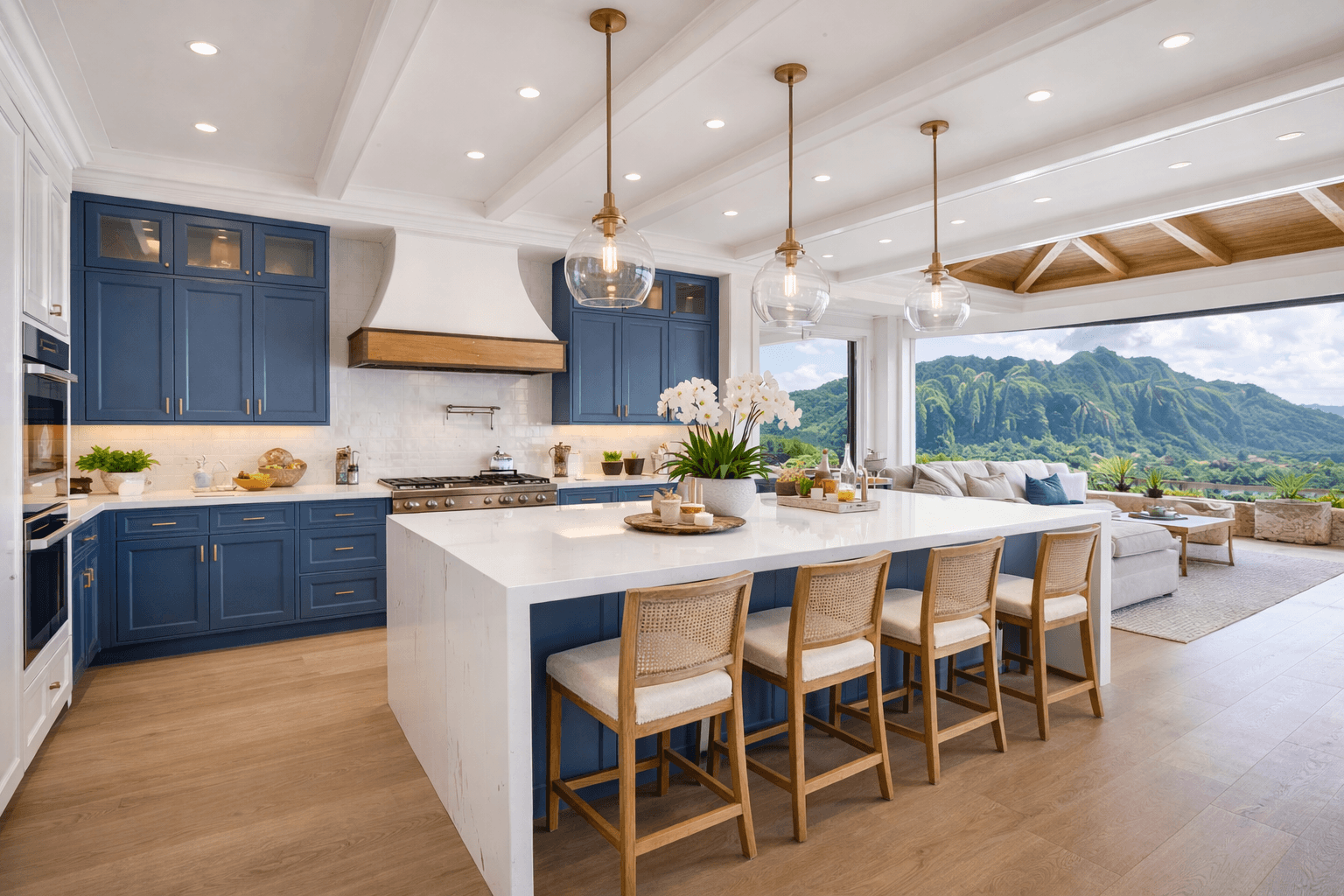 Modern kitchen with blue cabinets, white marble island, wooden stools, and lush mountain views.
