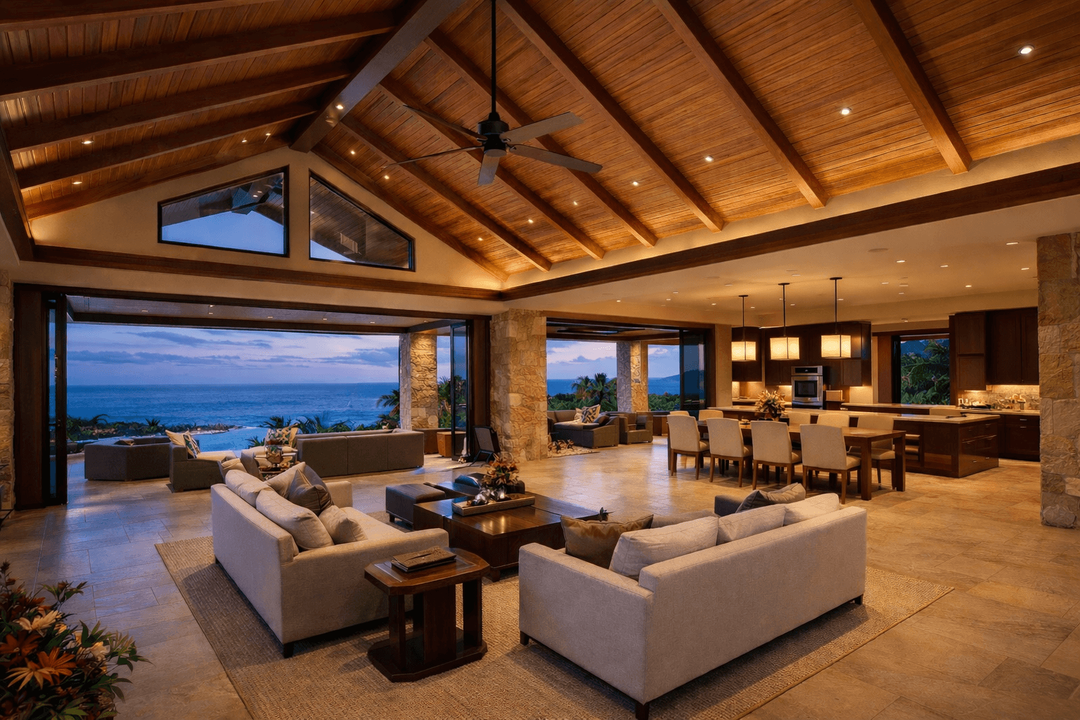 Luxurious open-concept living area with vaulted wood ceilings and panoramic ocean views at dusk.